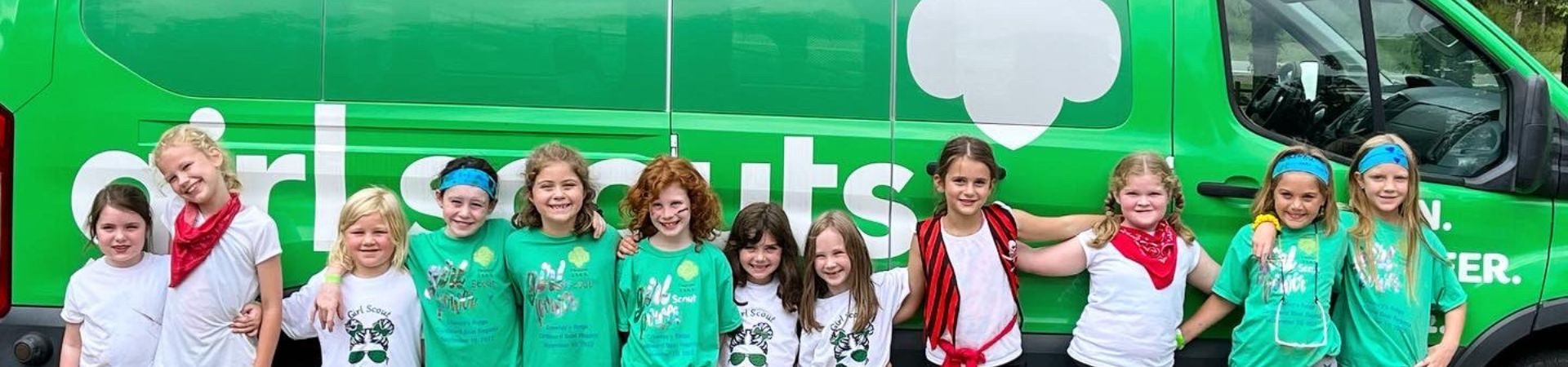  Girls stand in front of Girl Scout van with arms around shoulders 