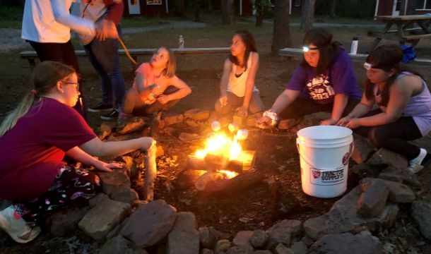 group of young girls around a campfire