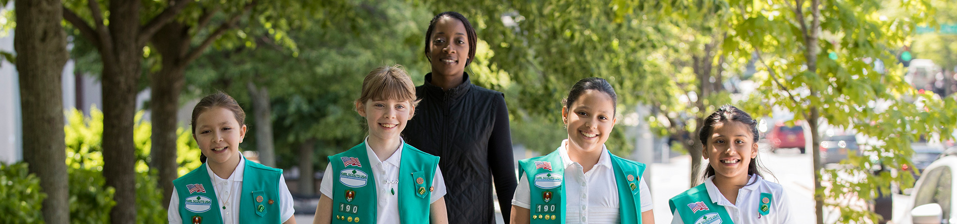  group of girl scouts with adult volunteer standing behind 