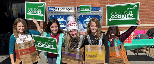 Girl Scouts holding cookie boxes
