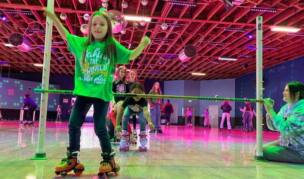 Girl at a roller rink who just rolled under a stick