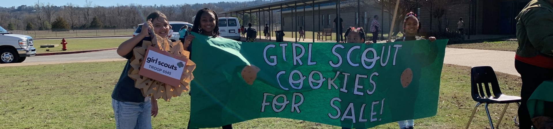  three girls at a Girl Scout cookie booth wearing cookie costumes 