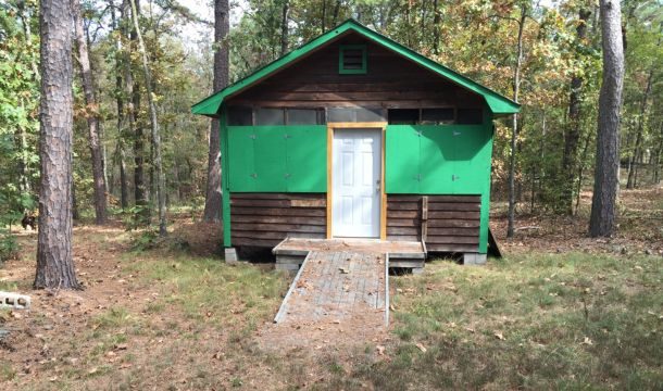 front of a small cabin at Radford House girl scout property