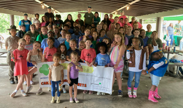 large group of Girl Scouts and volunteers posing inside a picnic pavillion