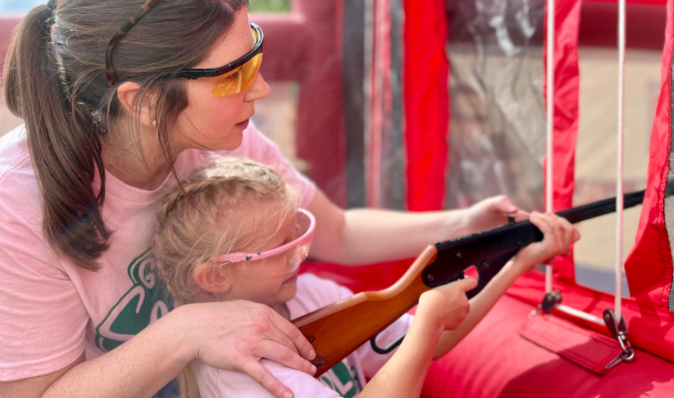 adult helps girl shoot bb gun