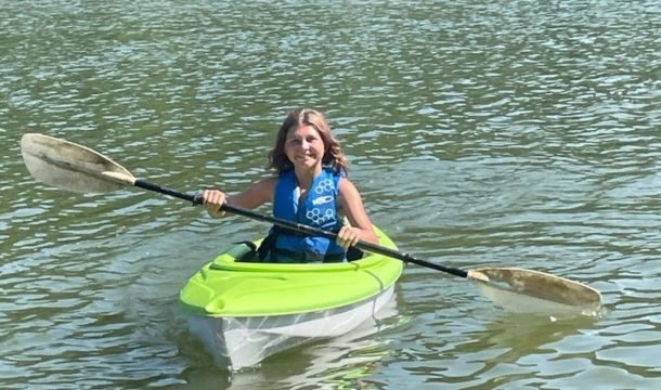 girl paddling a lime green and white kayak in a lake