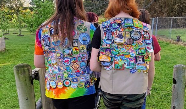 two older girl scouts from behind showing girl scout vests covered in patches