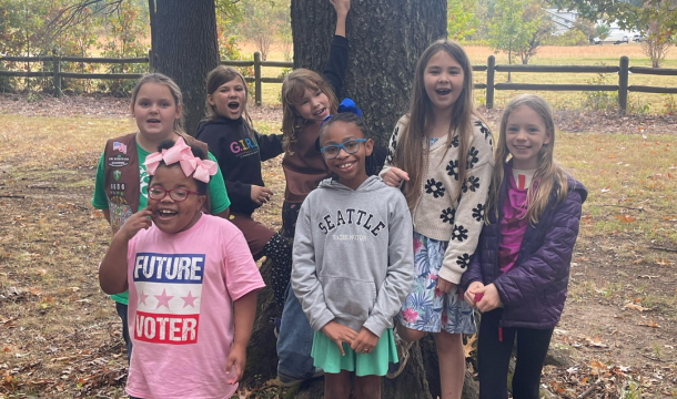 7 young Girl Scouts posing outside in front of a tree