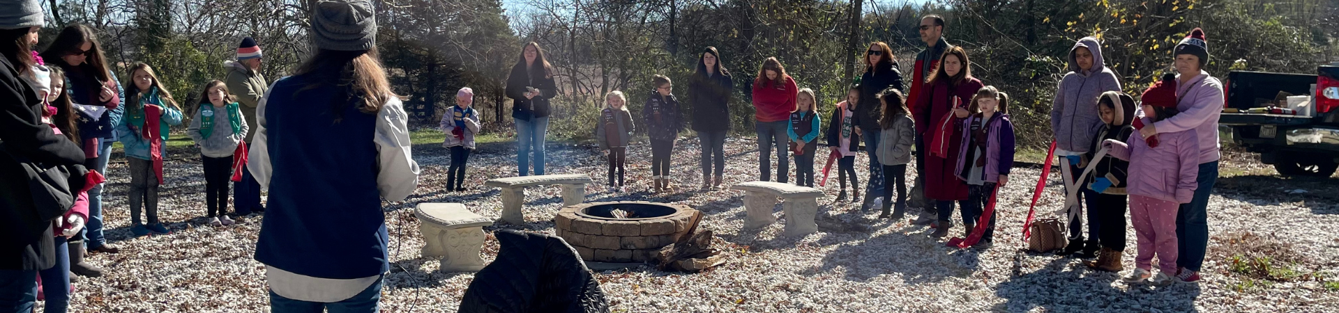  large group of girls and families gathered around a campfire 