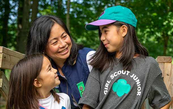 multi-age girl scout troop with volunteers standing in front of a lakeshore